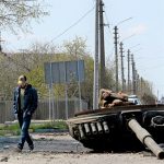 Civilian walks past destroyed tank in Ukrainian village of Skybyn, northeast of Kyiv on May 2, 2022