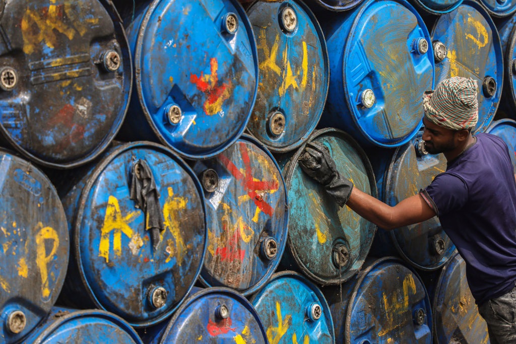 A worker is seen washing empty oil drums for recycling at a warehouse in Dhaka., Bangladesh. (Photo by Md Manik/SOPA Images/LightRocket via Getty Images)