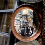 A wall mirror's reflection shows Iranians shop at the bazaar of Tajrish in northern Tehran, Iran, January 2023. Photo by ATTA KENARE / AFP via Getty Images