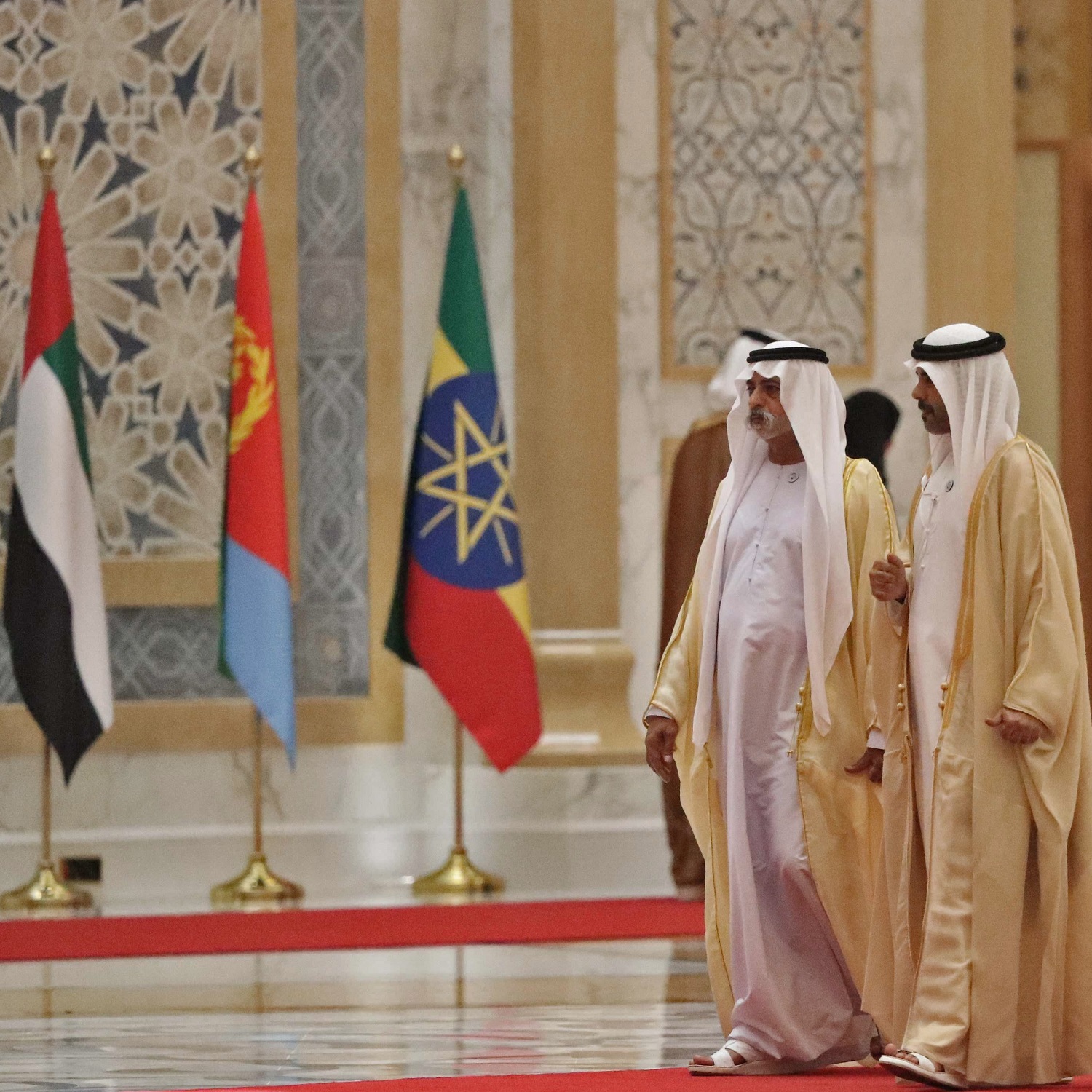 Emirati ministers gather at the presidential palace in the UAE capital Abu Dhabi in July 2018 to receive the visiting Ethiopian prime minister and Eritrean president, with state flags in the background