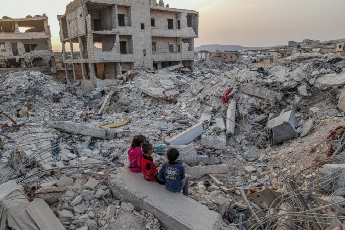 Children are seen sitting amongst the rubble of buildings destroyed by the earthquake in the city of Jenderes in Aleppo, northwestern Syria (February 2023)