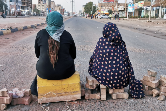 Sudanese women sit atop a brick barricade
