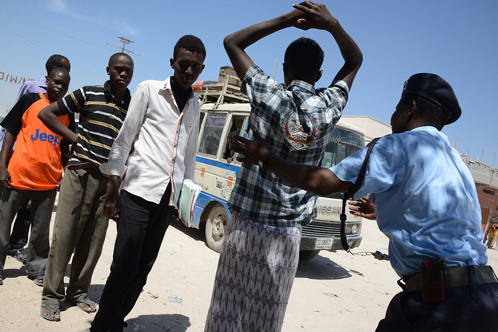 A Somali soldier frisks civilians at a checkpoint in Mogadishu