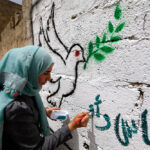 Yemeni artist paints a pro-peace graffiti on a wall