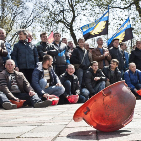 A group of men sit on the ground holding flags