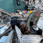 A woman cooks breakfast in the rubble of her house