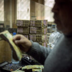 An employee works in front of stacks of Syrian pounds at the exchange department at the Central Bank Of Syria