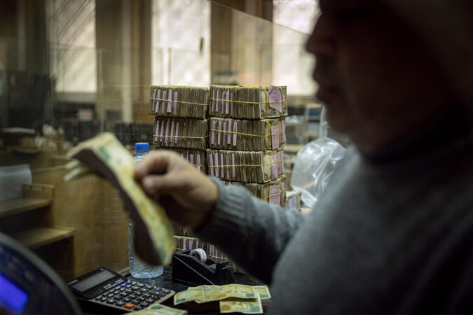 An employee works in front of stacks of Syrian pounds at the exchange department at the Central Bank Of Syria