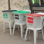 Three ballot boxes balanced on chairs