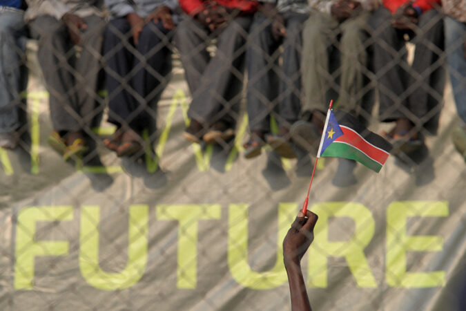 A hand waves a South Sudan flag in front of the word 'future'