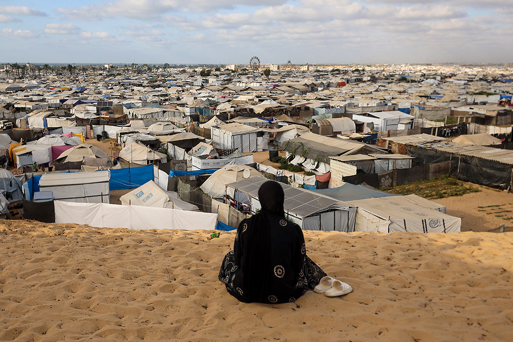 A Palestinian woman sits overlooking a camp for displaced people in Khan Yunis in the southern Gaza Strip