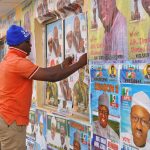 A man sticks a poster on a wall