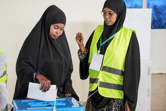 A woman casts her vote as an official looks on