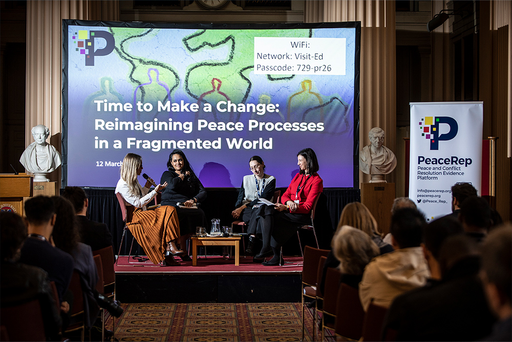 Conference panelists sit on a stage in front of an audience